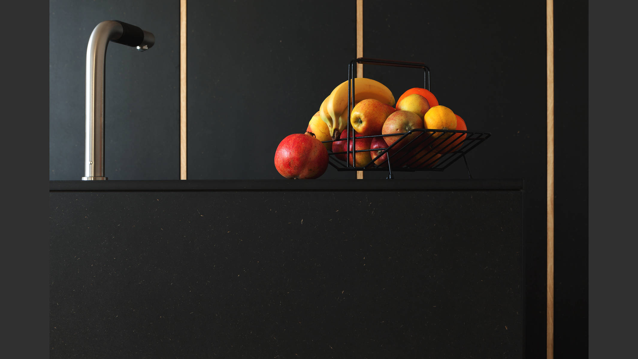 Eine schwarze Küche mit leuchtenden Früchten in rot und gelb. © Martin Geier
